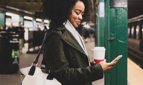 a woman holding a cup and a bag in a subway station area